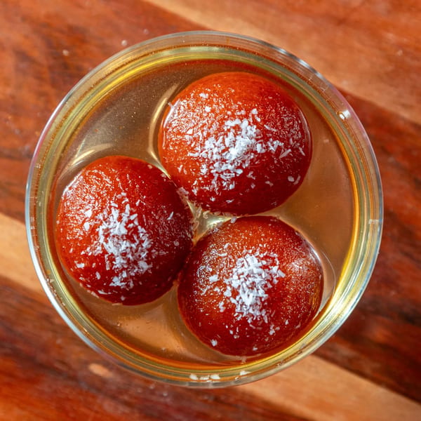 Three gulab jamun, Indian fried dough balls, in syrup with coconut flakes, from Taste of Mumbai.